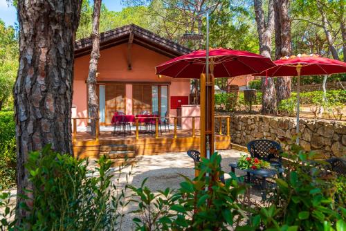 una casa con due ombrelloni rossi e un patio di Camping Lacona Pineta a Capoliveri