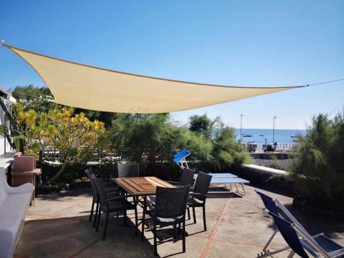 a patio with a table and chairs under a canopy at Villa Mareblu Luxury Holiday Apartment direttamente sul mare in Stromboli