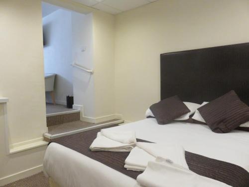 a bedroom with a large white bed with a black headboard at Stuart hotel in Blackpool