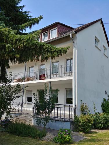 ein weißes Gebäude mit einem Balkon und Bäumen in der Unterkunft Gästehaus Koblenz in Koblenz