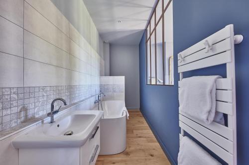 La salle de bains est pourvue d'un lavabo blanc et d'un mur bleu. dans l'établissement Luxurious Wine Estate Saint-Emilion Grand Cru with private swimming pool, à Saint-Hippolyte