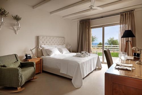 um quarto com uma cama, uma cadeira e uma janela em Camvillia Resort Messinia em Vounaria