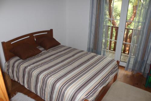 a bed with a striped blanket in a room with a window at Cantinho do Bouço Velho in Couto de Baixo