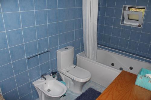 a blue tiled bathroom with a toilet and a bath tub at Cantinho do Bouço Velho in Couto de Baixo