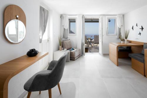 a white living room with a chair and a mirror at Santorini Princess Spa Hotel in Imerovigli