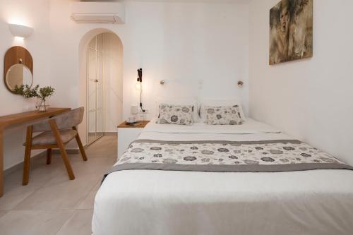 a white bedroom with a bed and a desk at Santorini Princess Spa Hotel in Imerovigli