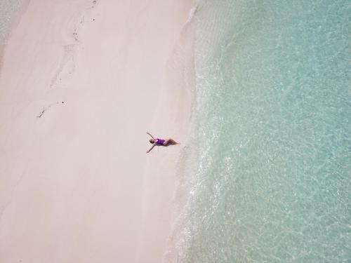 an overhead view of a person on a beach next to the ocean at Ithaa Dhigurah Maldives in Dhigurah
