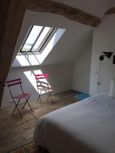 a bedroom with two chairs and a bed in a attic at Orangerie du chateau de Quemigny sur Seine in Quemigny-sur-Seine