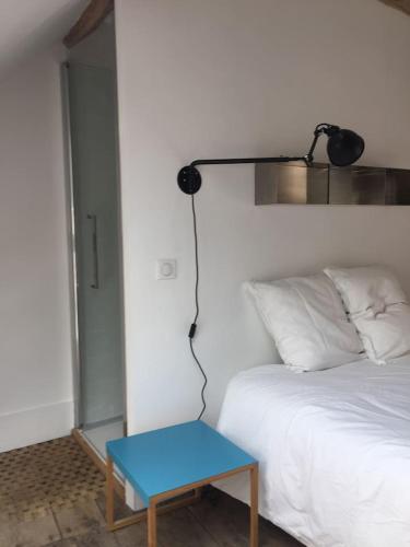 a bed with a blue table next to a lamp at Orangerie du chateau de Quemigny sur Seine in Quemigny-sur-Seine