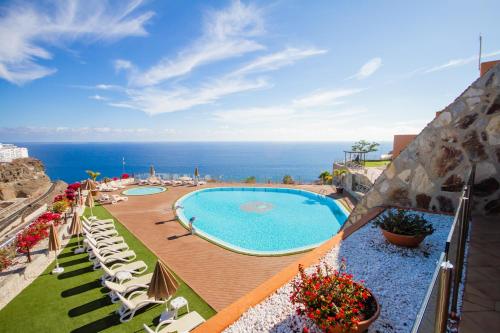 uitzicht op een zwembad met stoelen en de oceaan bij Serenity Amadores in Puerto Rico de Gran Canaria