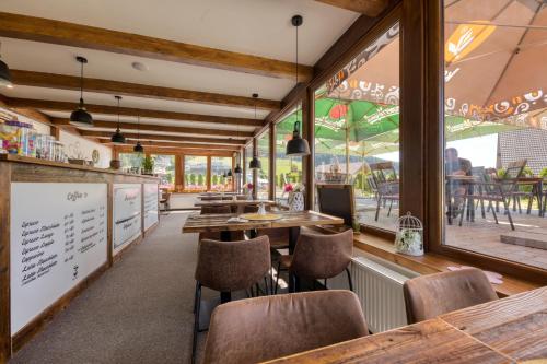 um restaurante com mesas, cadeiras e janelas em Penzion Neubauer em Ostružná