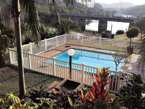 una piscina con una valla blanca alrededor en The Tweni Waterfront Guest Lodge, en Port Shepstone