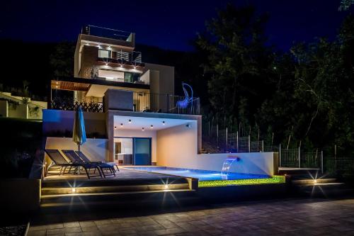 a house with a swimming pool at night at Villa AltaVista - Seaview & Relax with Heated Pool & MiniGolf in Opatija