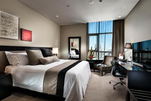 柏斯的住宿－珀斯輝盛閣國際公寓，酒店客房配有一张床、一张书桌和一台电视。