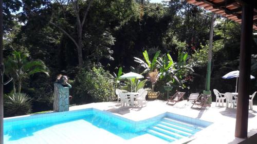 uma piscina com cadeiras, uma mesa e um guarda-sol em Pousada Vila Cintra em Pirenópolis