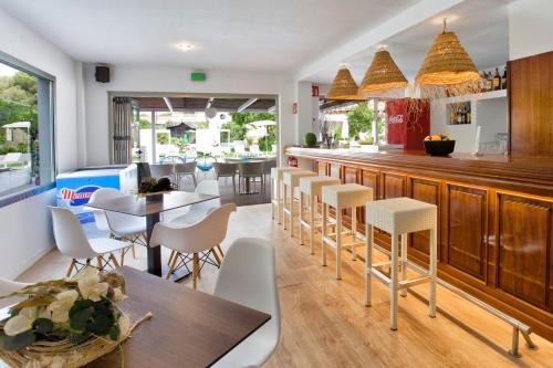 a restaurant with a bar with white chairs and tables at Flacalco Hotel & Apartments in Cala Ratjada
