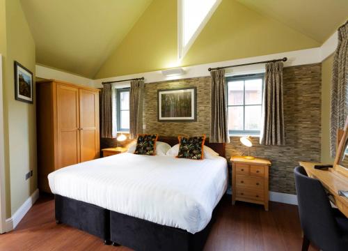 um quarto com uma grande cama branca e 2 janelas em Les Ormes Resort em St Brelade