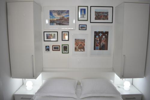 a white bedroom with a bed and pictures on the wall at Apartments Svilan in Trogir