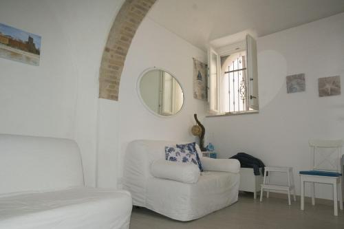 a white living room with a chair and a mirror at Residenza Giannini a Termoli in Termoli