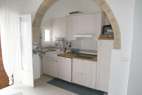 una cucina con armadi bianchi e un arco di Residenza Giannini a Termoli