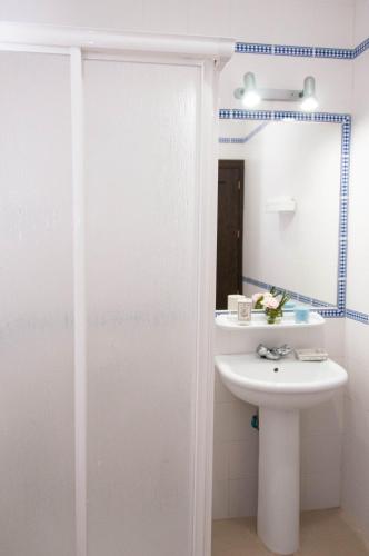a white bathroom with a sink and a mirror at Apartamentos Conil Alquila in Conil de la Frontera