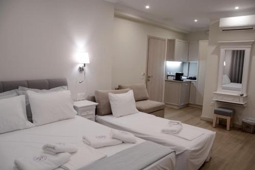 a hotel room with two beds with white sheets at LEVANTA HOTEL SPETSES in Spetses