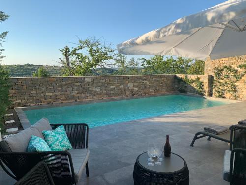 a pool with a couch and a table and an umbrella at Exceptional 5 Star villa with breathtaking views, Sauna and fitness studio in Momjan