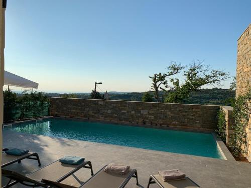 a swimming pool with chairs and a brick wall at Exceptional 5 Star villa with breathtaking views, Sauna and fitness studio in Momjan