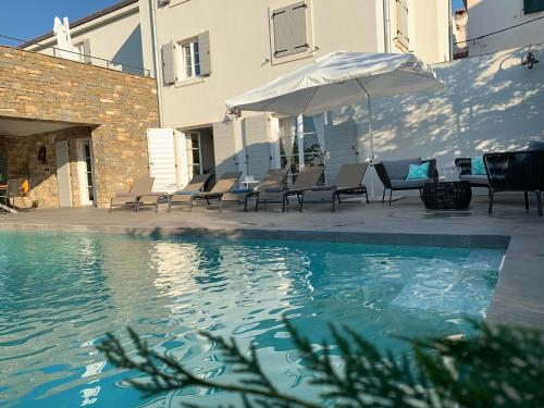 a swimming pool with chairs and an umbrella at Exceptional 5 Star villa with breathtaking views, Sauna and fitness studio in Momjan