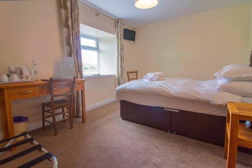 a bedroom with a bed and a desk and a window at The Twice Brewed Inn in Bardon Mill