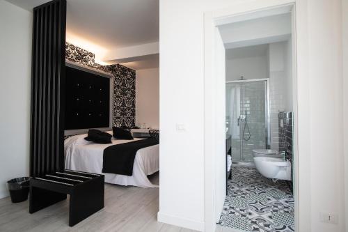 a bedroom with a bed and a bathroom with a tub at Hotel La Compagnia Del Viaggiatore in LʼAquila