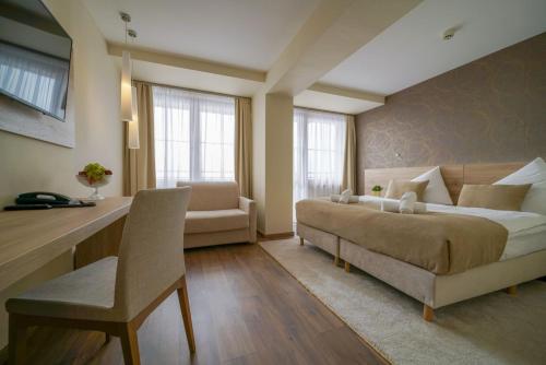 a bedroom with a bed and a couch and a desk at Grand Hotel BELLEVUE in Smokovce