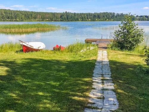 a stone path leading to a lake with a boat at Holiday Home Eden by Interhome in Kuusa