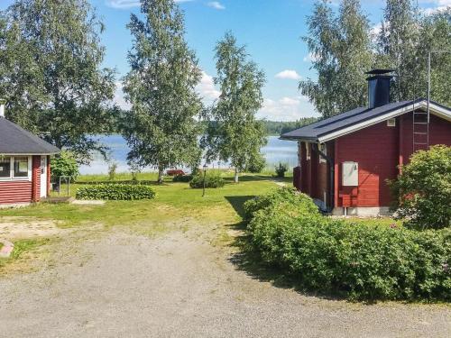 een rood huis met een meer op de achtergrond bij Holiday Home Eden by Interhome in Kuusa