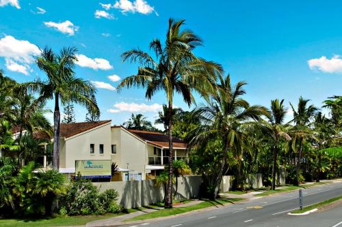 a house on the side of a street with palm trees at Le Court Villas in Noosa Heads