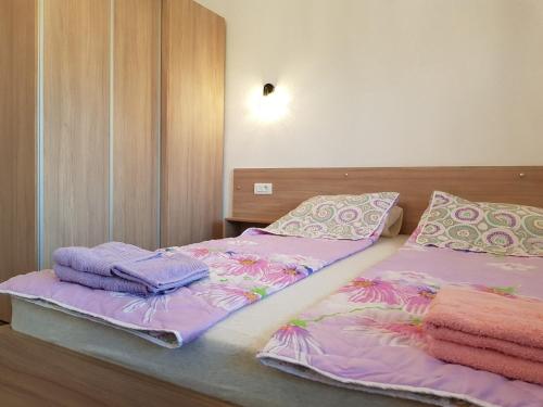 - 2 lits dans une chambre avec des draps et des serviettes violets dans l'établissement Apartment Dimeski, à Ohrid