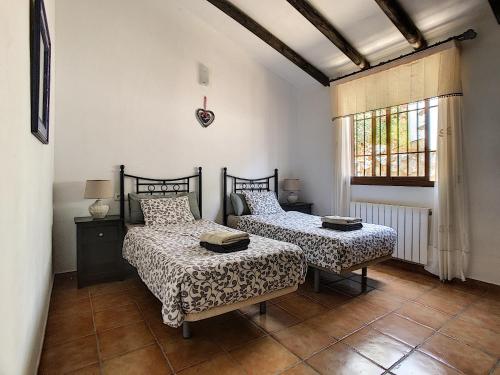 1 dormitorio con 2 camas y ventana en Casa Lobera Casas Rurales, en Canillas de Aceituno