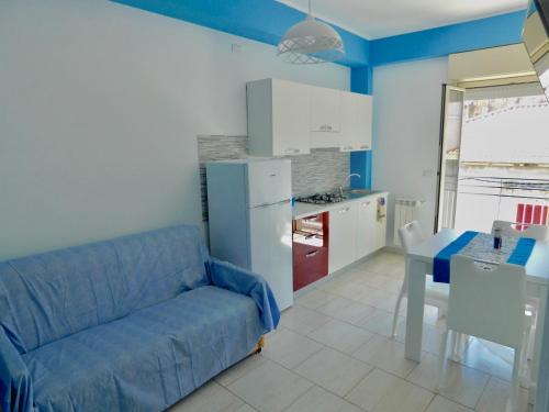 sala de estar con sofá azul y cocina en Vanilla Apartments, en Giardini Naxos