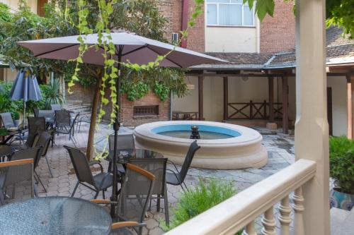 a fountain in a patio with chairs and an umbrella at Hotel Nata in Tbilisi City