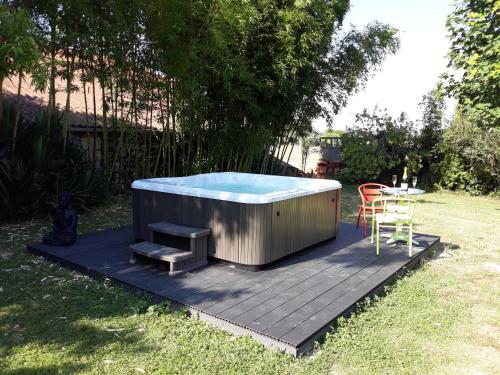 a hot tub sitting on a deck with a table at La Massonnière Gîte et chambres d'hôtes in Mondion