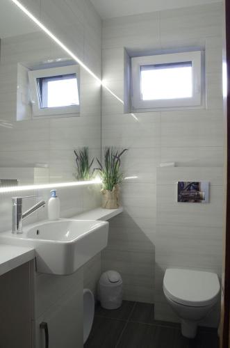 a white bathroom with a sink and a toilet at Pokoje gościnne U Jadzi in Chałupy