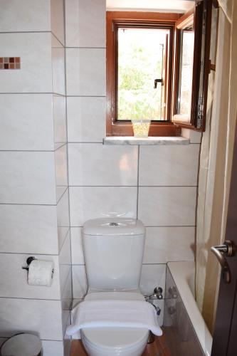 a white bathroom with a toilet and a window at Sun Villa in Neon Oitilon