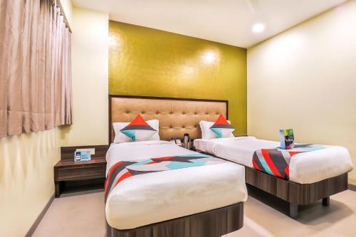 a bedroom with two beds and a yellow wall at FabHotel Landmark Residency - Nr MIDC Turbhe in Navi Mumbai