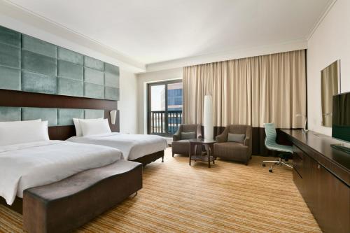 a hotel room with two beds and a desk at Traders Hotel, Abu Dhabi in Abu Dhabi