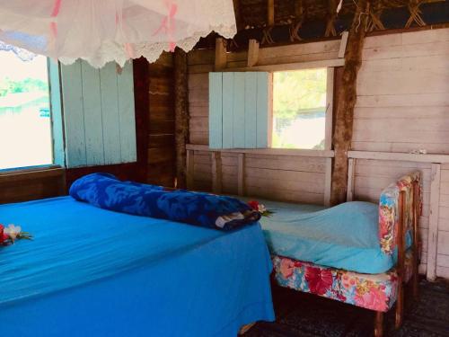 two beds in a room with two windows at Malakati Village Beach House in Nacula Island