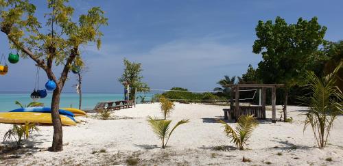 a beach with a yellow surfboard on the sand at PERLA Dhangethi in Dhangethi