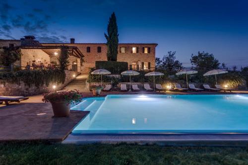 a swimming pool in front of a building with umbrellas at Fattoria Fibbiano in Terricciola