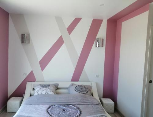 a bedroom with pink and white walls and a bed at Le Temps d'un Rêve in Eauze