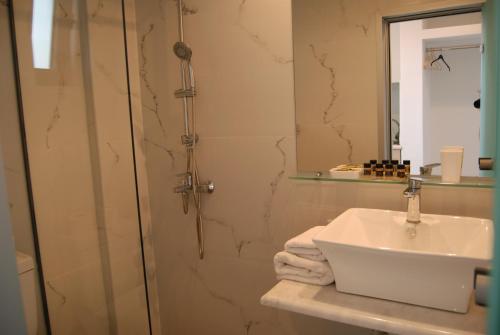 y baño con lavabo y ducha con espejo. en Artemis Studios, en Faliraki