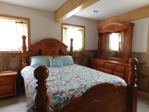 a bedroom with a wooden bed with a dresser and a mirror at No View Farm in Rumford